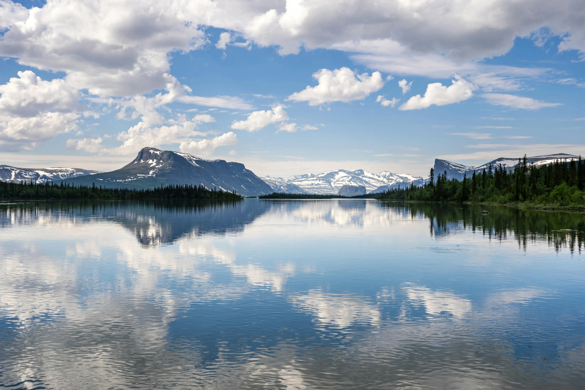 the large mountains are covered in clouds on the water