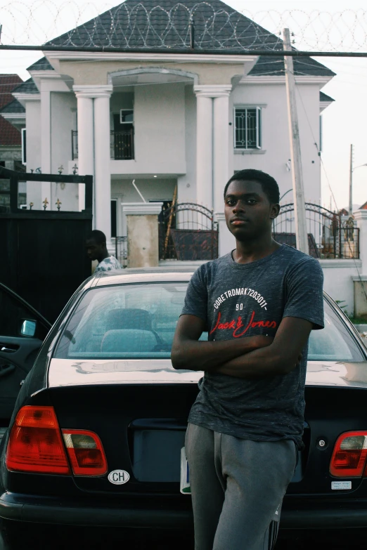 a man stands in front of a car in the driveway