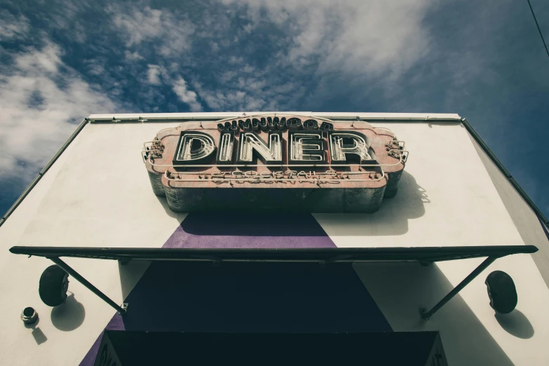 a large sign for an eatery hanging from the side of a building