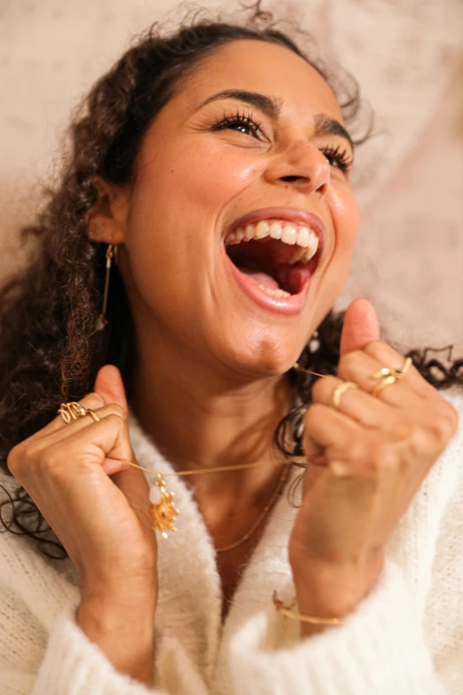 a woman laughing and holding two ring in both hands