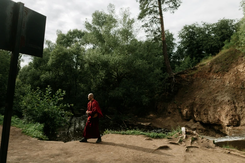 a man walking away from a waterfall near a forest