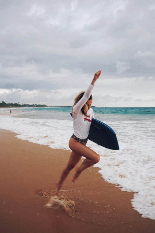 the woman is on the beach jumping with her surfboard