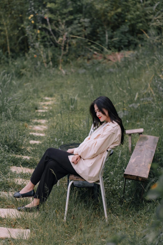 a woman sits on a chair in the woods