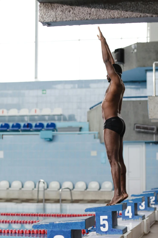 man in black shorts jumping off diving platform into the water