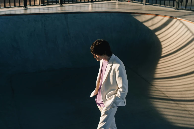 a boy in white clothes skateboarding on a ramp