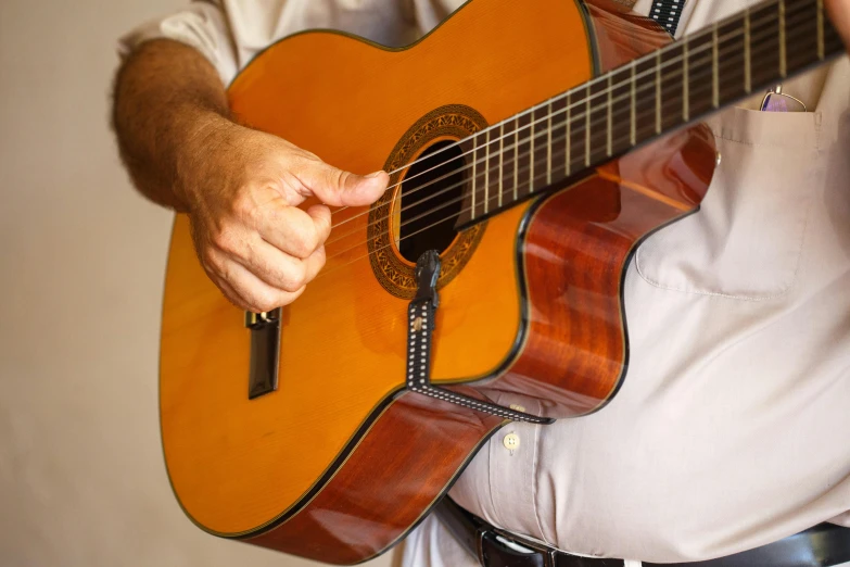 a man is holding an acoustic guitar and playing it