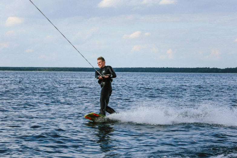 man standing on his board holding the handle of an oar and water skiing