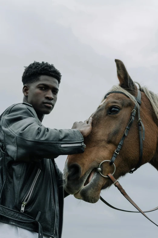 a man in black jacket petting a horse