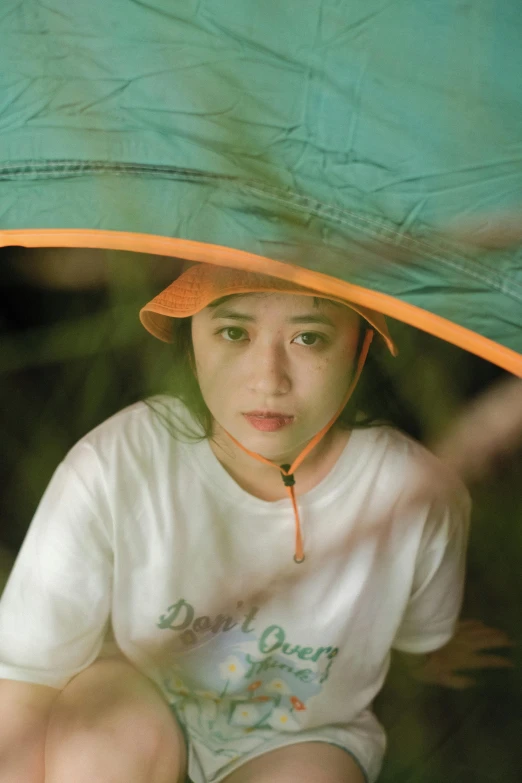 a girl holding an umbrella while sitting on the ground