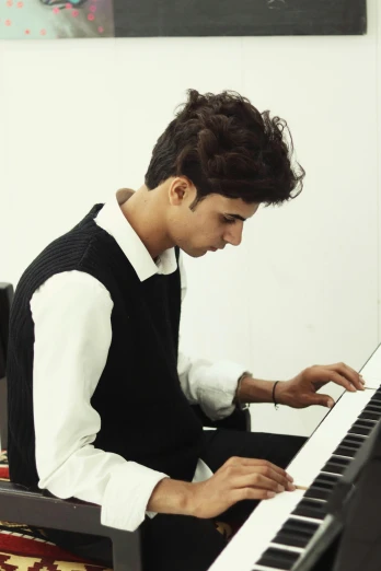a young man in vest sitting at a piano