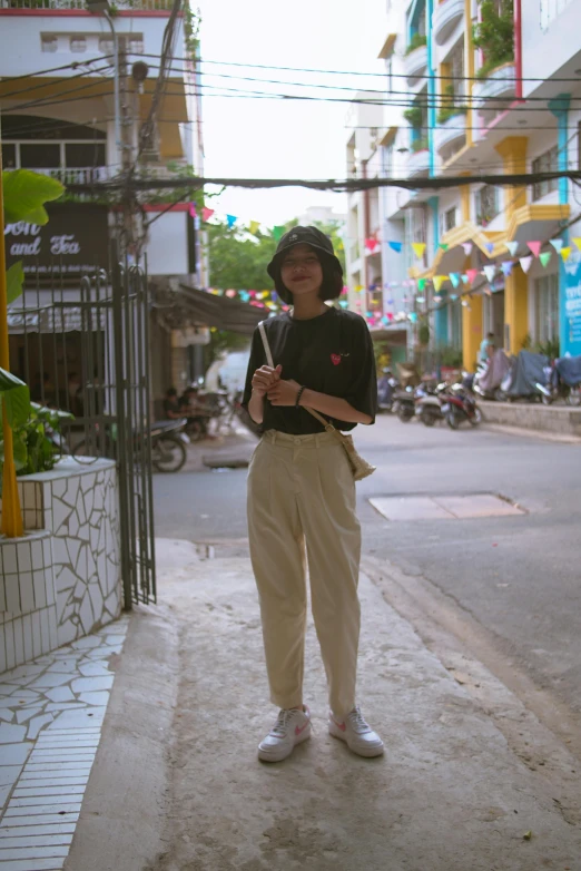 a woman standing on the side of a road in front of a fence