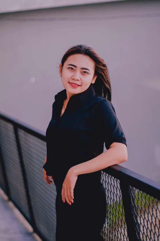 a woman leaning up against a fence in front of a building