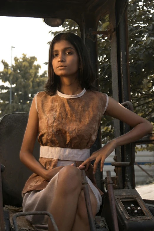 a woman sitting on a small, old chair next to an outdoor structure