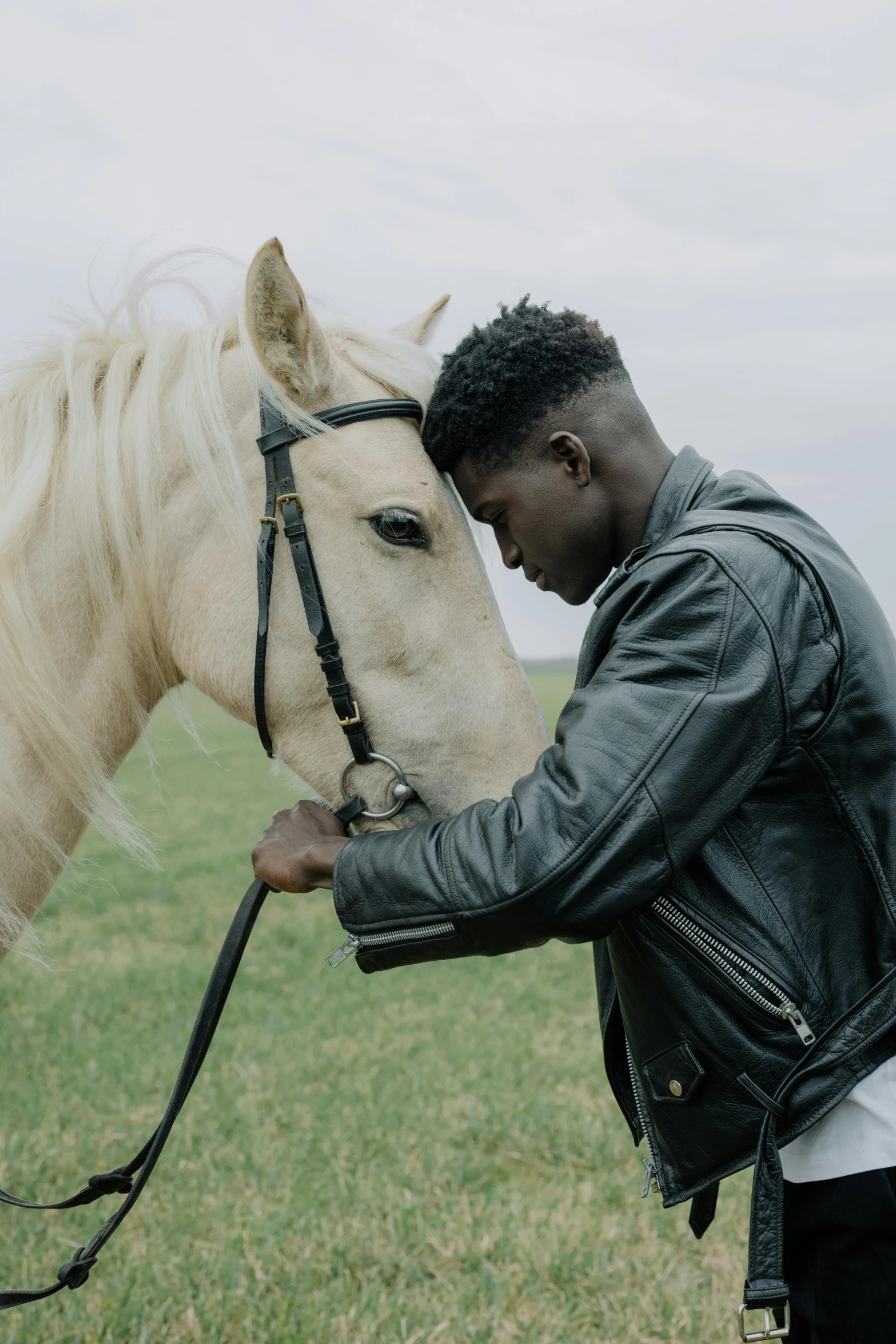 a man in a leather jacket petting a horse