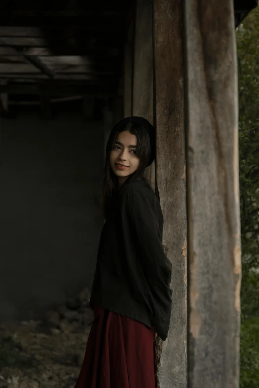 a young woman posing next to a long wooden structure