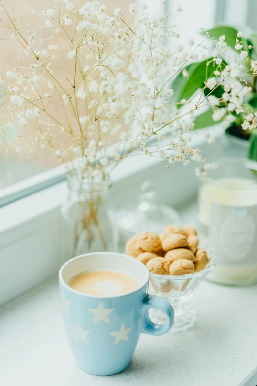 a cup of coffee and some small nuts on the window sill