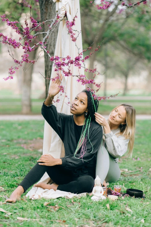 the couple is sitting under a blossomy tree and their engagement pos