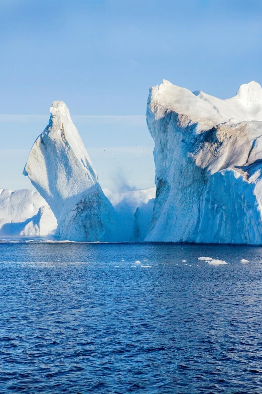 an iceberg in the ocean, surrounded by many snow - capped rocks