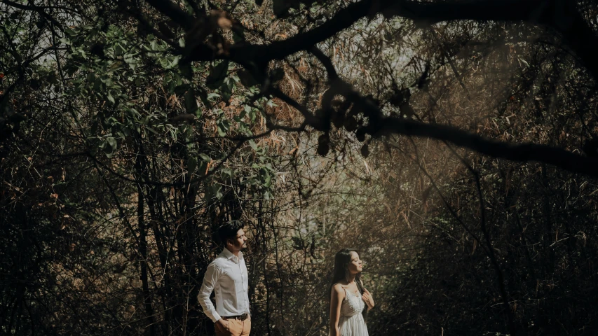 man and woman standing in a dark forest