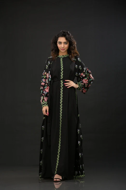 a woman poses for the camera wearing a long dress with floral embroidered sleeves