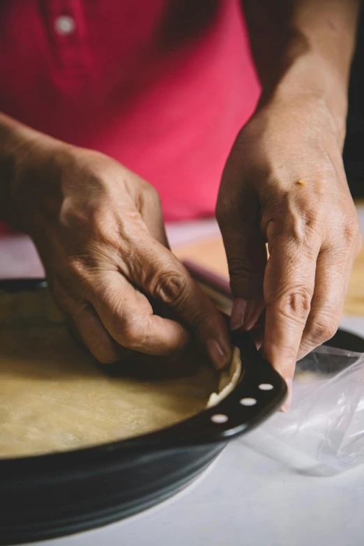 an old woman hands working on a pizza