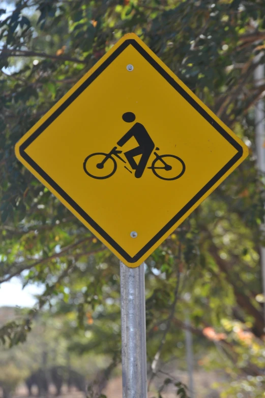 a yellow pedestrian crossing sign near some trees