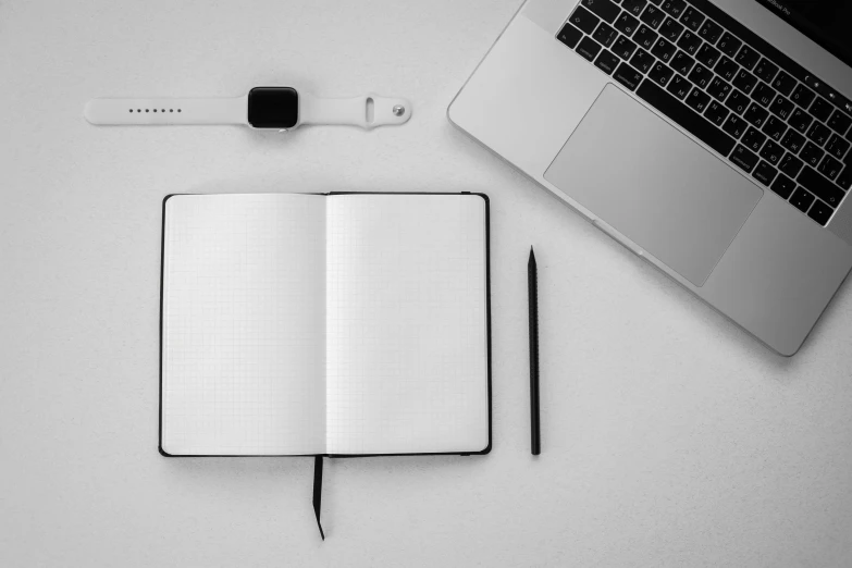 a laptop and pen are sitting next to an open notebook