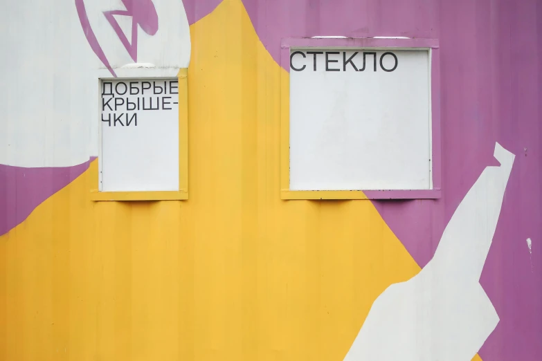 a white and yellow building with two pieces of white paint with letters on it