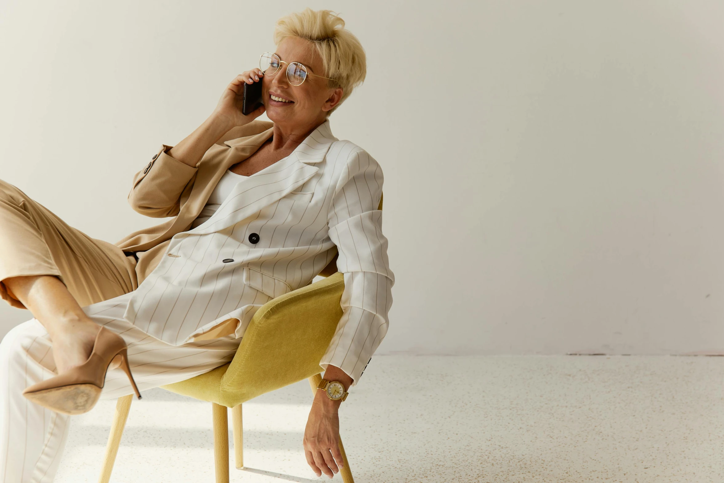 a woman sitting on top of a yellow chair while talking on a cell phone