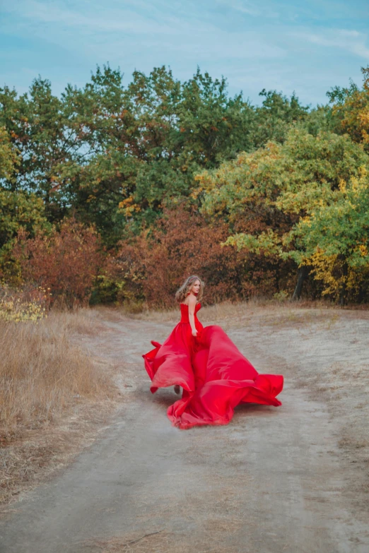 a  wearing a red flowing dress standing in a road