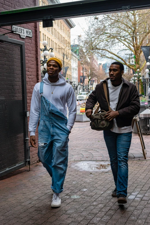 two people walking down a brick street under an overpass