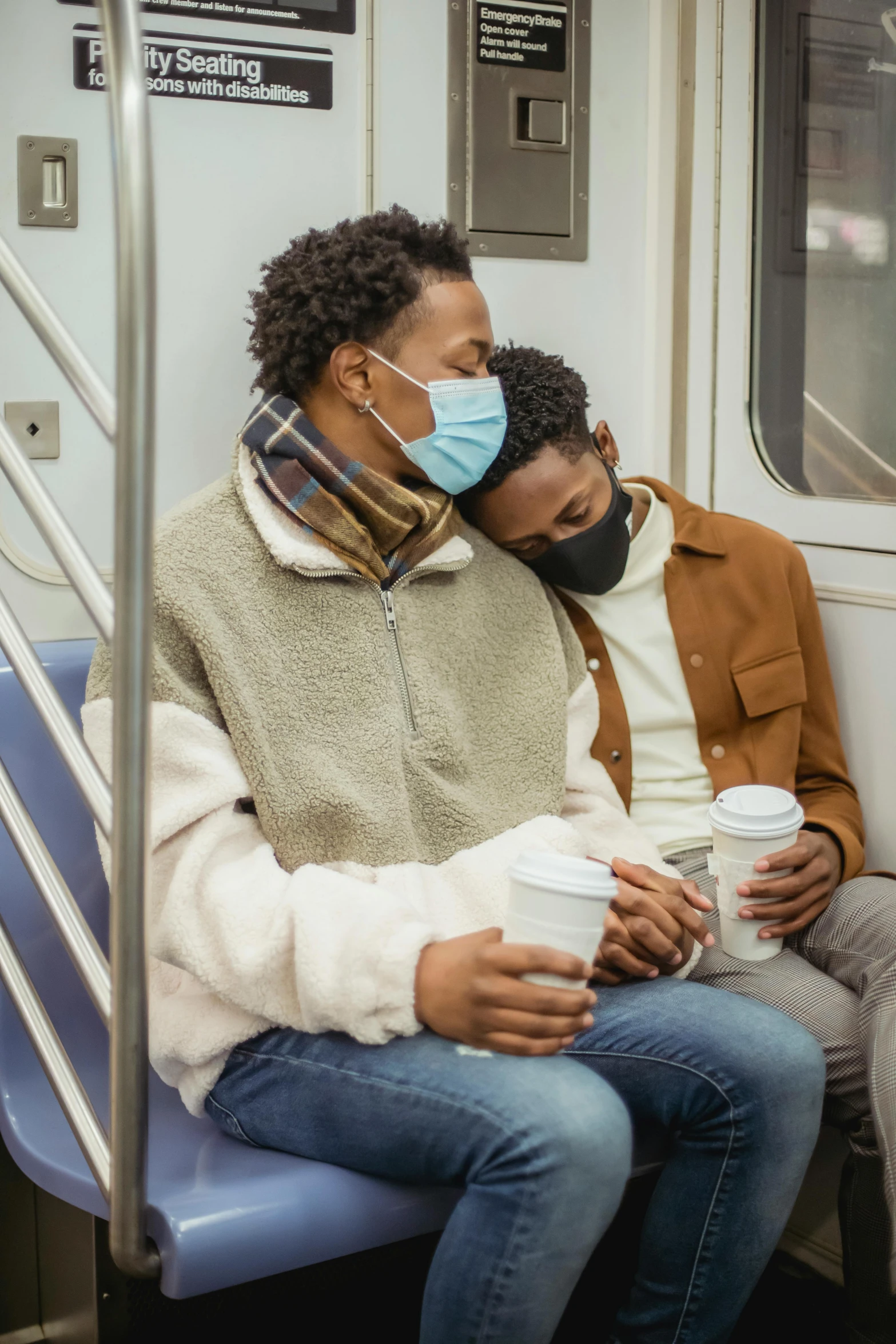 man in mask on subway train while holding a coffee cup