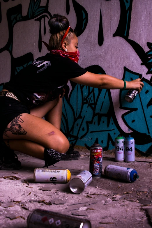 a woman painting graffiti in front of a wall