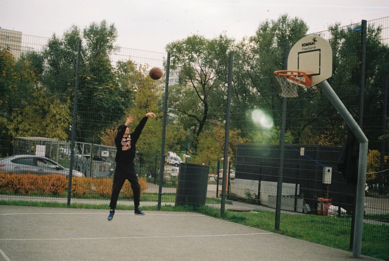 a young man playing with a basketball in the park