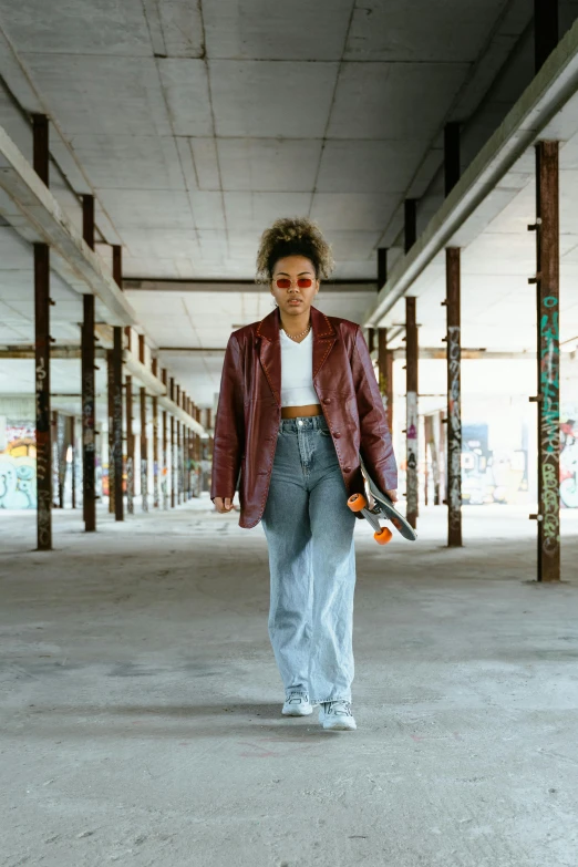 a woman with sunglasses and a jacket on is holding a skateboard