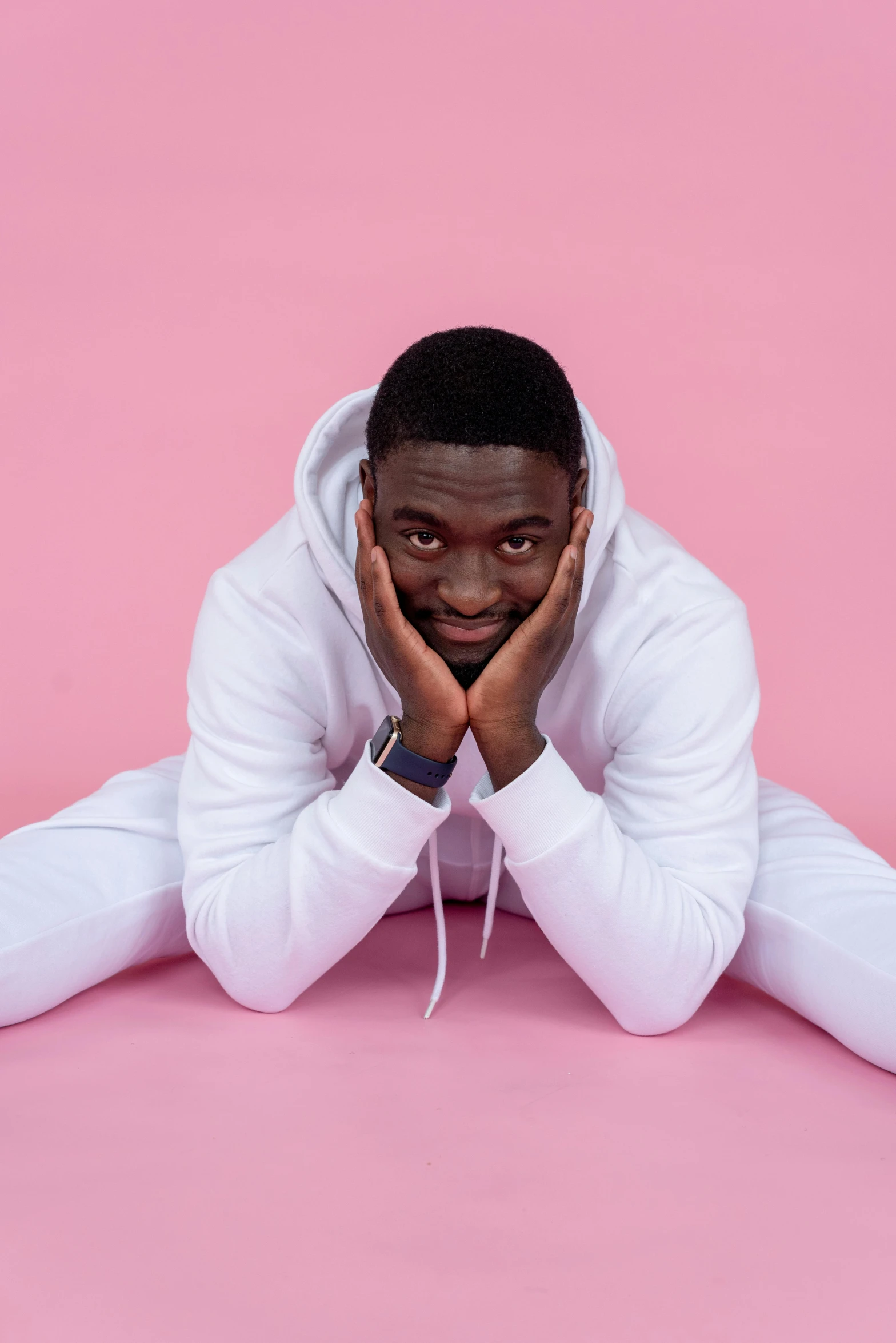 a man in white sits on pink with his hands under the face