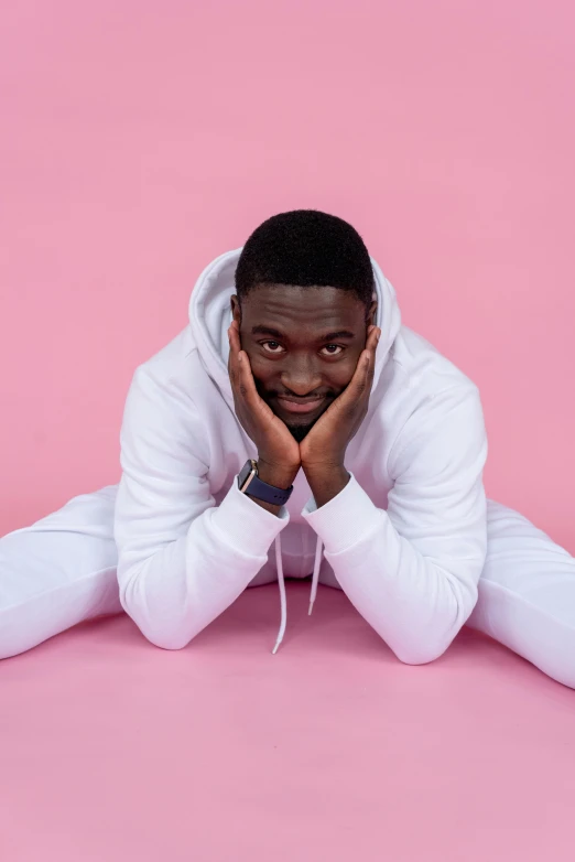 a man in white sits on pink with his hands under the face