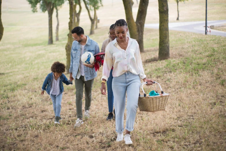 a family is walking down a path with a basket