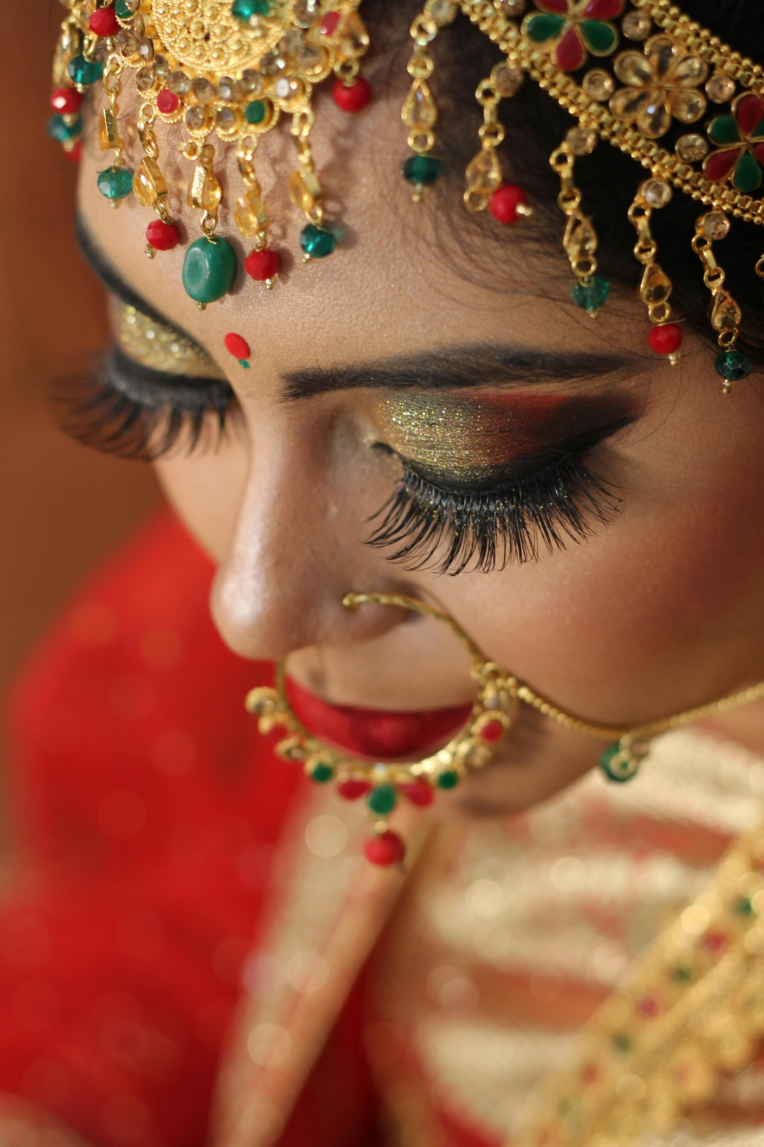 woman in a red veil with gold and green makeup