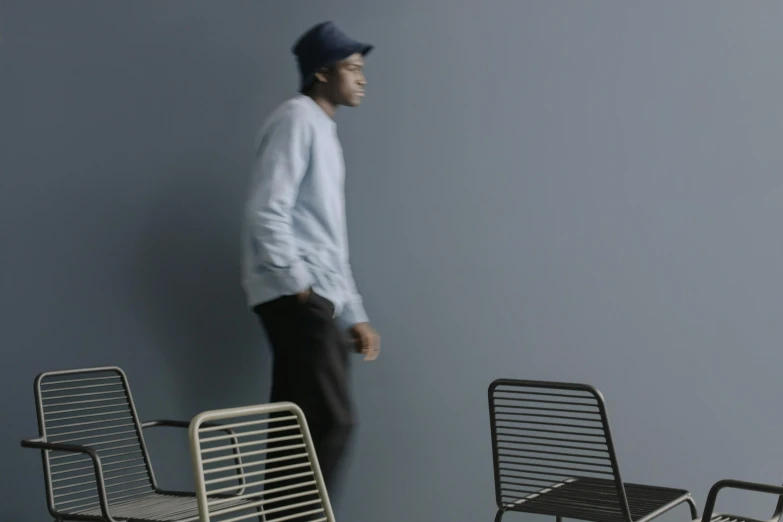 a young man walking near four lounge chairs