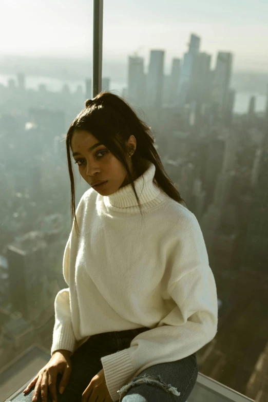 a young woman sits atop the edge of a high rise overlooking city