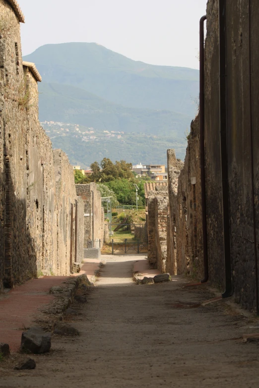 a stone building on one side and mountains in the background