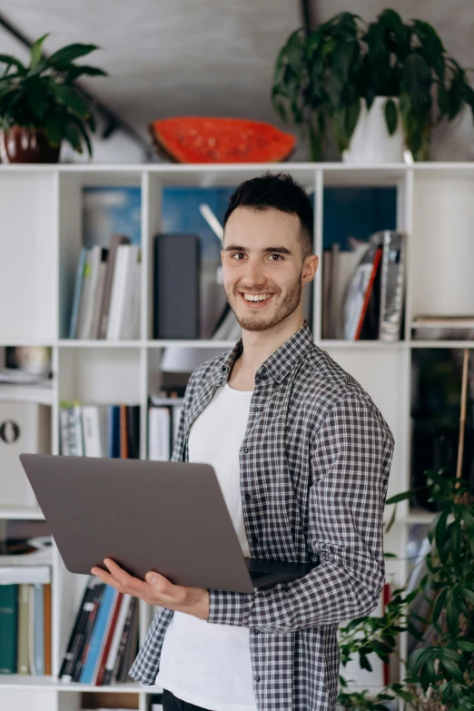 a man holding a laptop computer while smiling