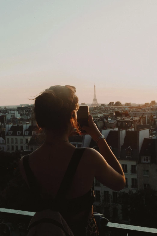 woman talking on phone in balcony overlooking the city skyline