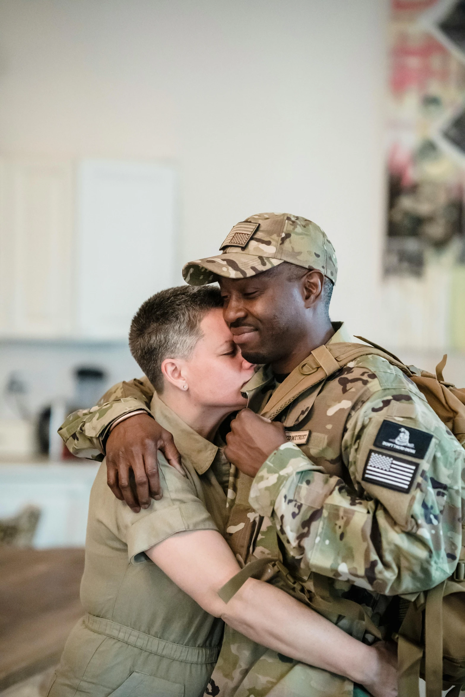 an army soldier hugging a young person in the middle of the kitchen