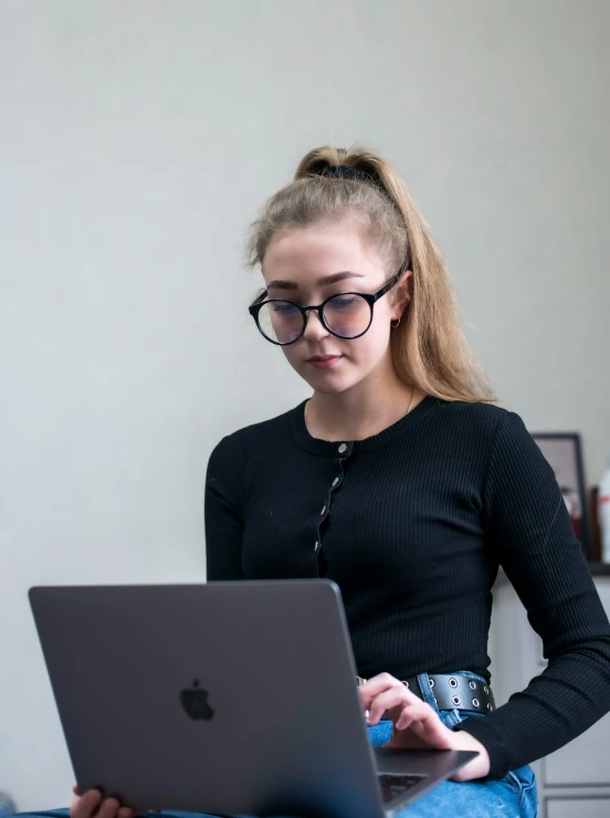 the girl is standing at a laptop on the table