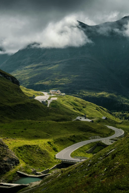 a road winds through green mountains during a cloudy day