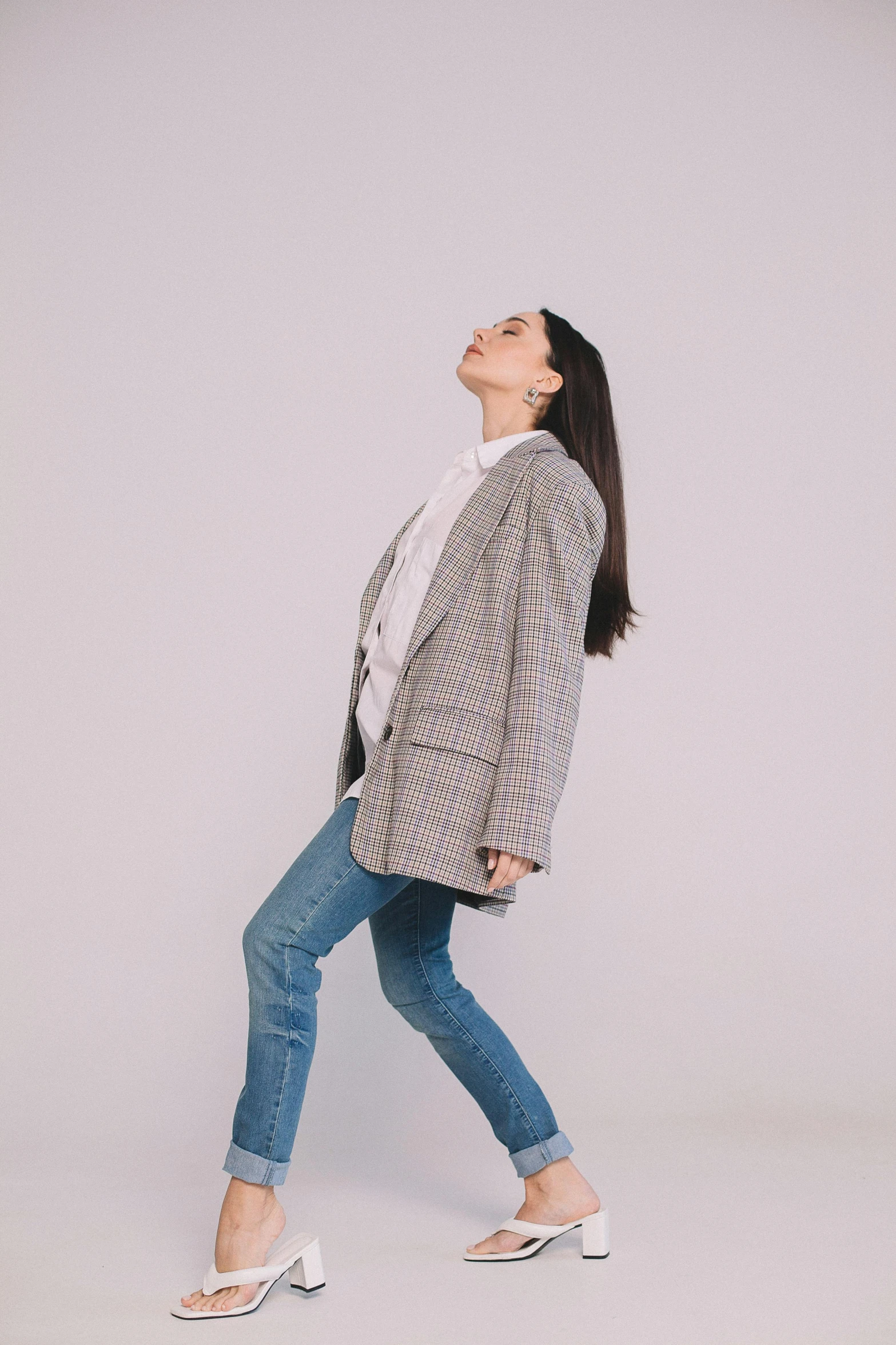 woman walking while wearing a plaid blazer over a white top