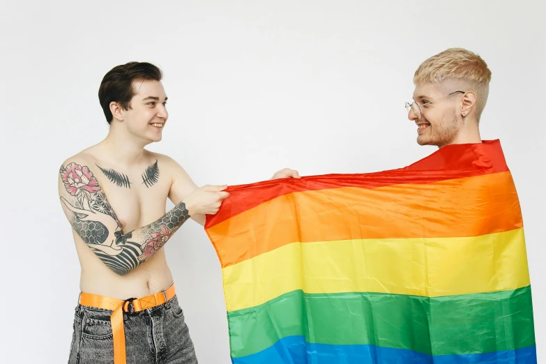 two men standing next to each other, one holding a rainbow flag