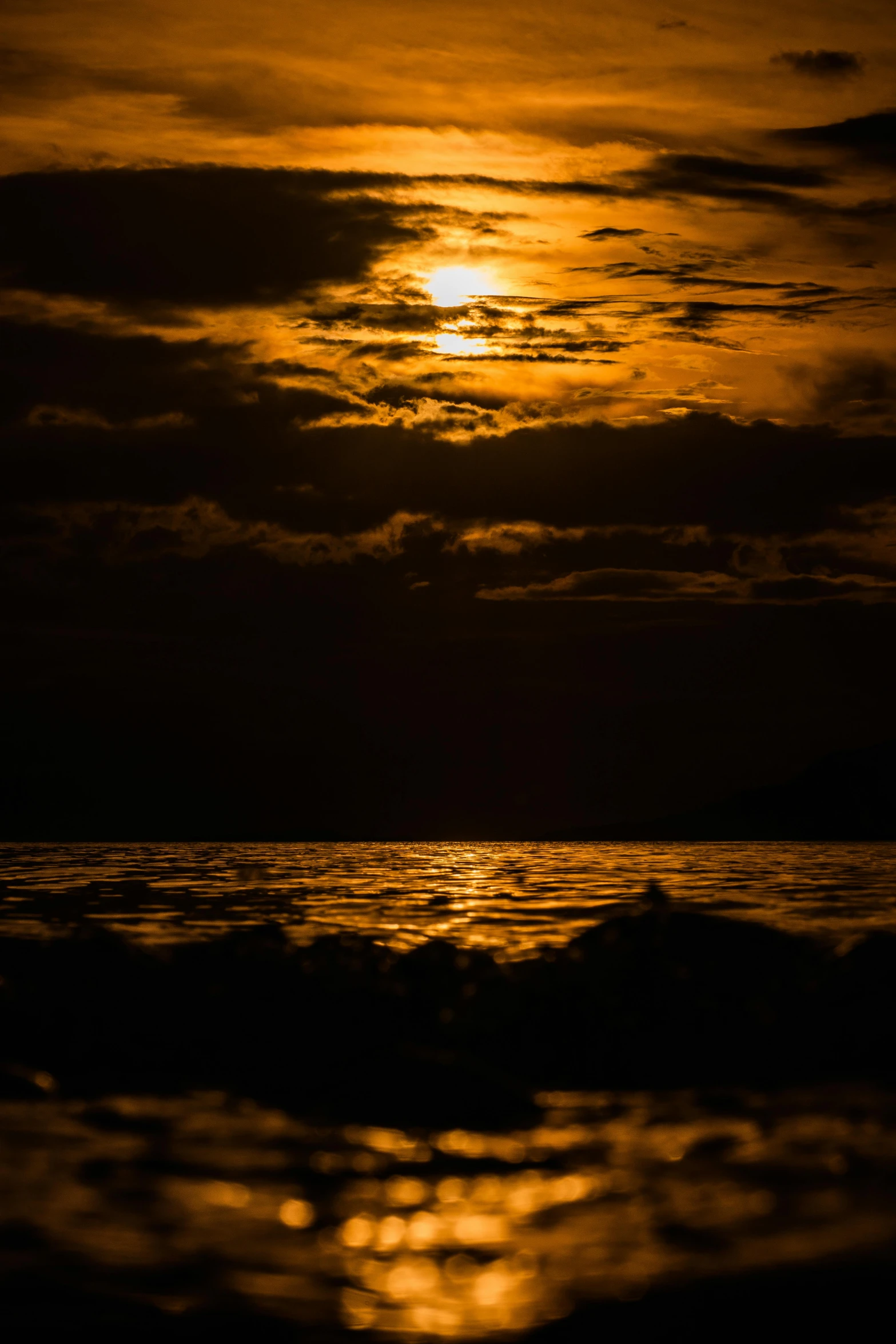 some clouds in the sky above water and sun setting